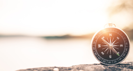 a compass sitting on a rock on a sunny day
