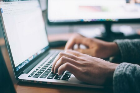 person's hands typing on laptop keyboard