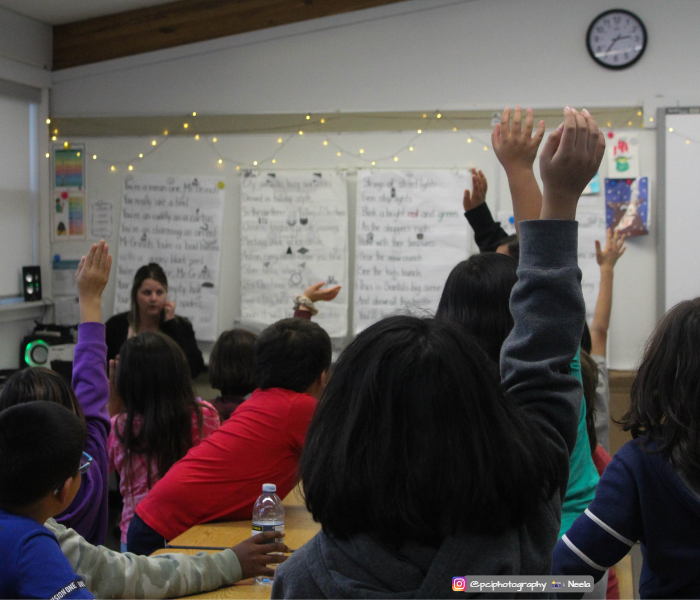 students in a classroom sitting listening to the teacher