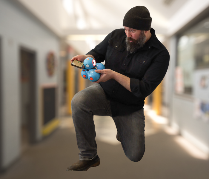 teacher holding a Dash Robot with an excited look on his face.