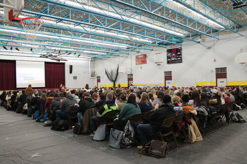 Crowd in a gym listening to a speaker